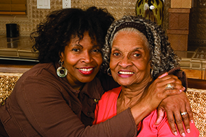 woman smiling with arm around elderly woman