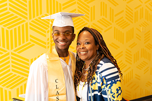 teen in cap and gown smiling with woman