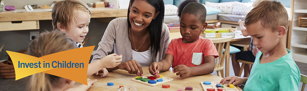 woman playing with blocks with children at a table