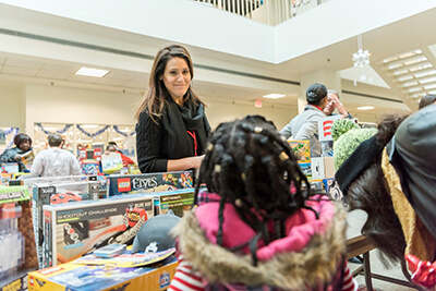 Volunteer helping child look through toys at holiday event