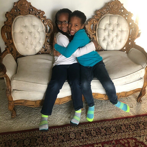 two sisters hugging and smiling on a couch