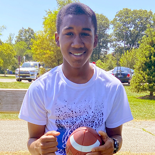 young man smiling and holding a football